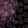 Close-up view of pink resin flower bead caps for jewelry making scattered on a dark background.