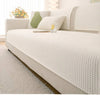 A white machine washable anti-slip sofa slipcover displayed on a bed with light bedding and natural light.