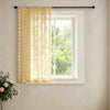 A sheer, cream-colored lace curtain with a wavy border hanging in a white window frame.