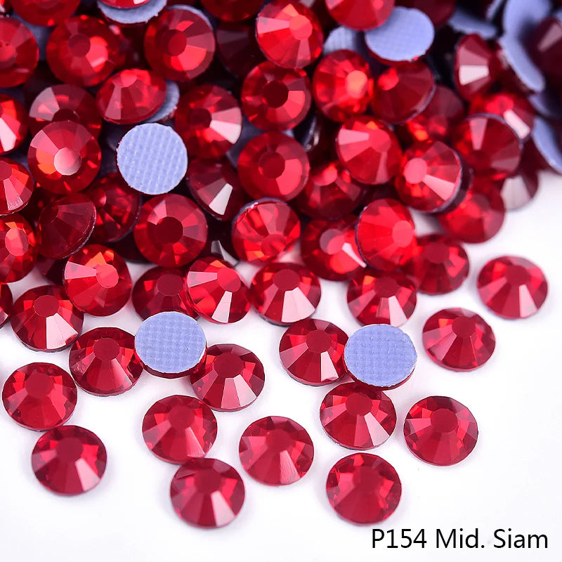 A close-up view of red and purple flatback glass rhinestones scattered on a white background.