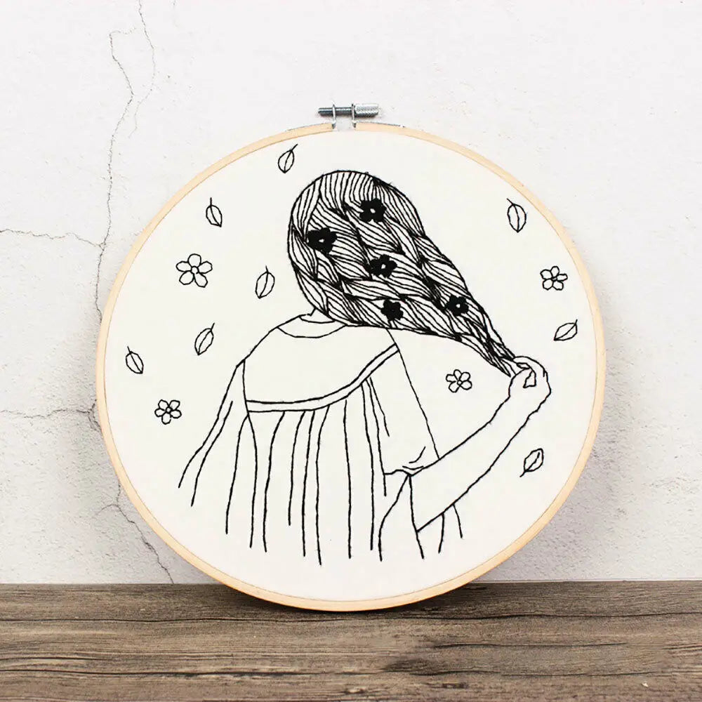 Black line drawing of a woman with long hair and flowers, used as an embroidery kit design.
