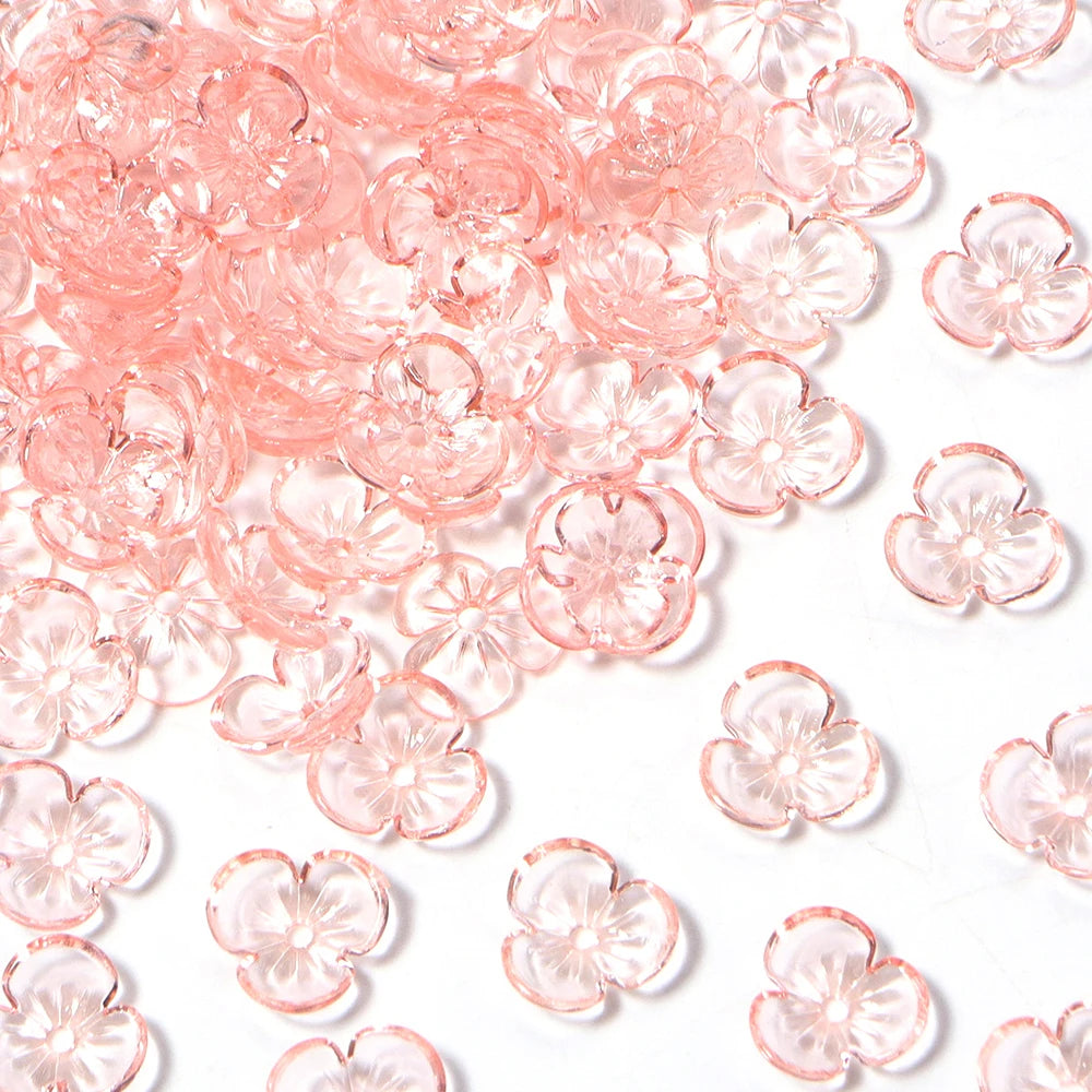 Pink resin flower bead caps scattered on a white background for jewelry making