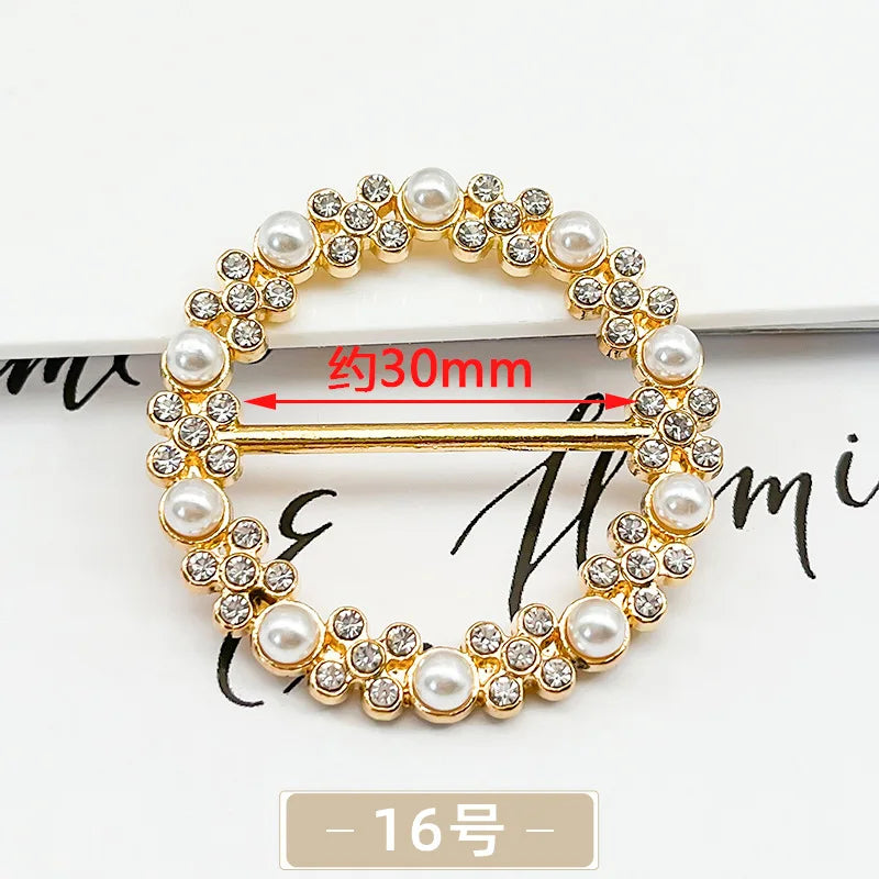 A gold-toned metal ring clip featuring small diamonds and pearl accents, shown with a measurement line.