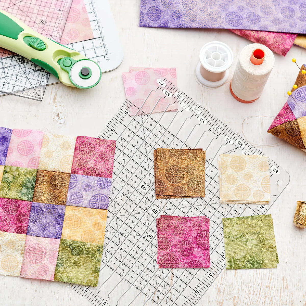 A precision acrylic quilting ruler with a dual scale and seam rail is shown alongside fabric squares, a sewing thread, and a 