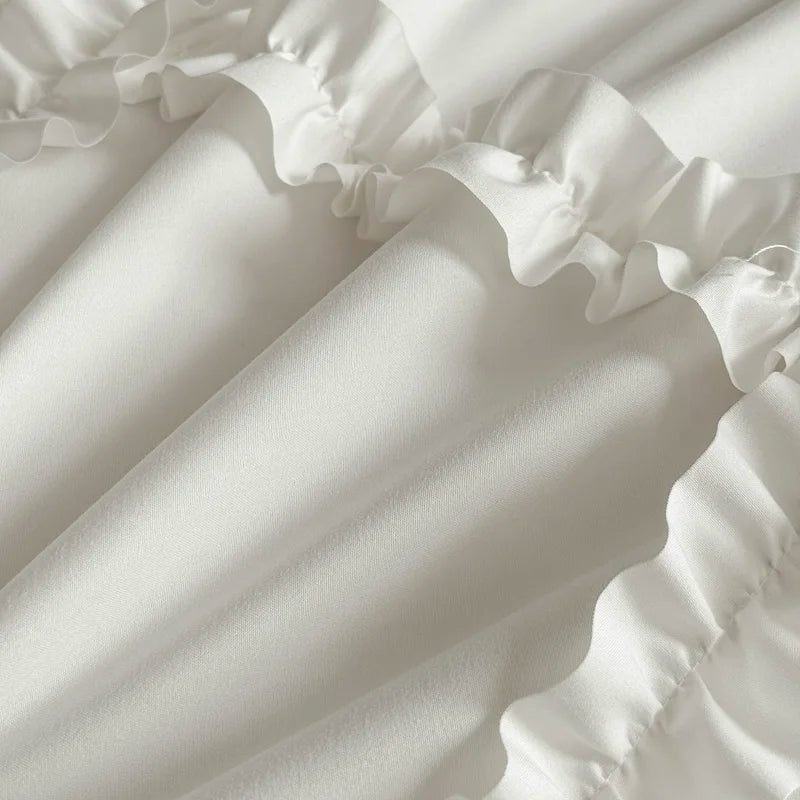A close-up of a white ruffled duvet cover set fabric showing soft folds and pleats.