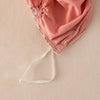 A pink pinch pleated duvet cover set with delicate lace trim and a sheer tie visible.
