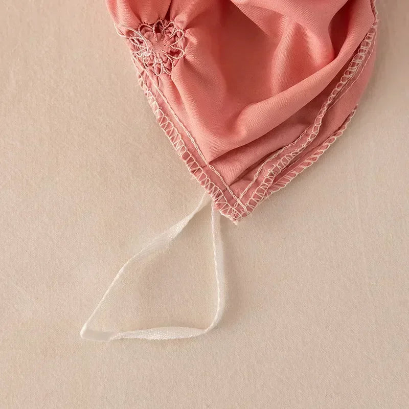 A pink pinch pleated duvet cover set with delicate lace trim and a sheer tie visible.