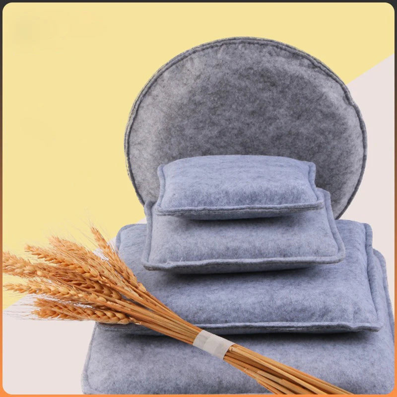 A stack of blue gray needle felting mats with a bundle of golden wheat stalks.
