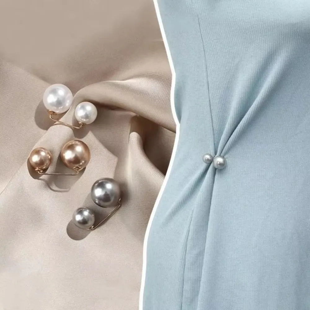 A close-up of a pearl brooch jewelry set featuring several white and gold-toned pearls on a light blue fabric.