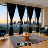 Four panels of black blackout curtains hanging in a window with a sunset view.