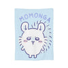 A light blue blanket featuring a cartoon character with large ears and a smiling expression, with the word MOMONGA above it.