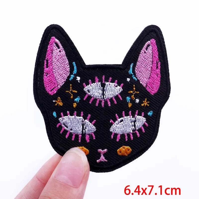 Black felt cat face embroidered with pink and white feathers and colorful thread details
