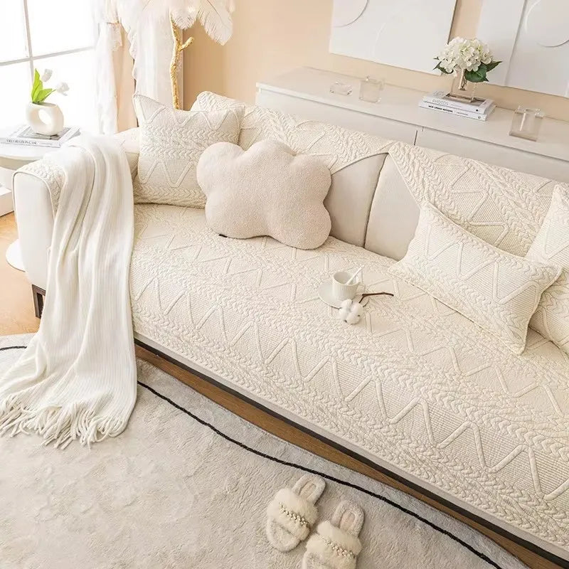 A cream woven sofa cover with a textured pattern displayed on a light-colored sofa.