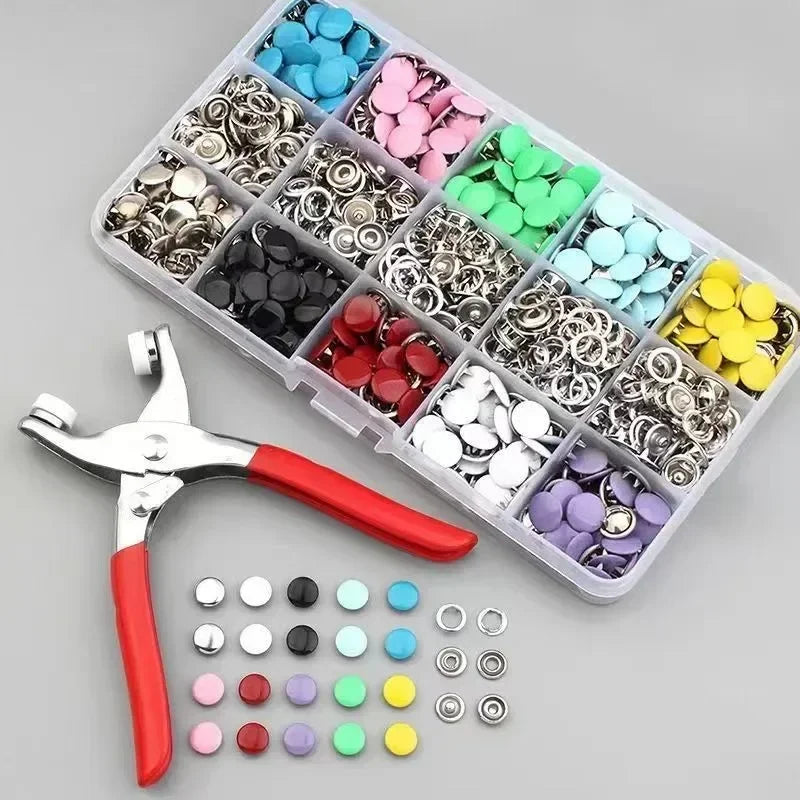A plastic tray filled with various colorful metal sewing buttons and a pair of pliers and assorted button components