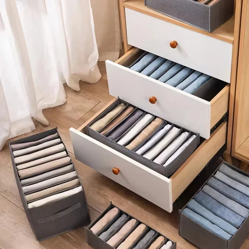 A wooden drawer organizer with multiple dividers for storing folded undergarments and accessories.