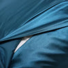 A close-up of a teal luxury mulberry silk pillow cover draped and folded.
