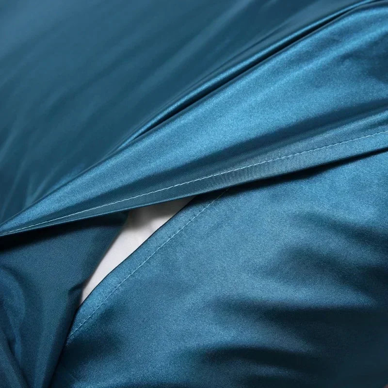 A close-up of a teal luxury mulberry silk pillow cover draped and folded.