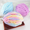 Three skeins of extra thick hand-knitted yarn in shades of blue, purple, and pink are displayed on a wooden tray.