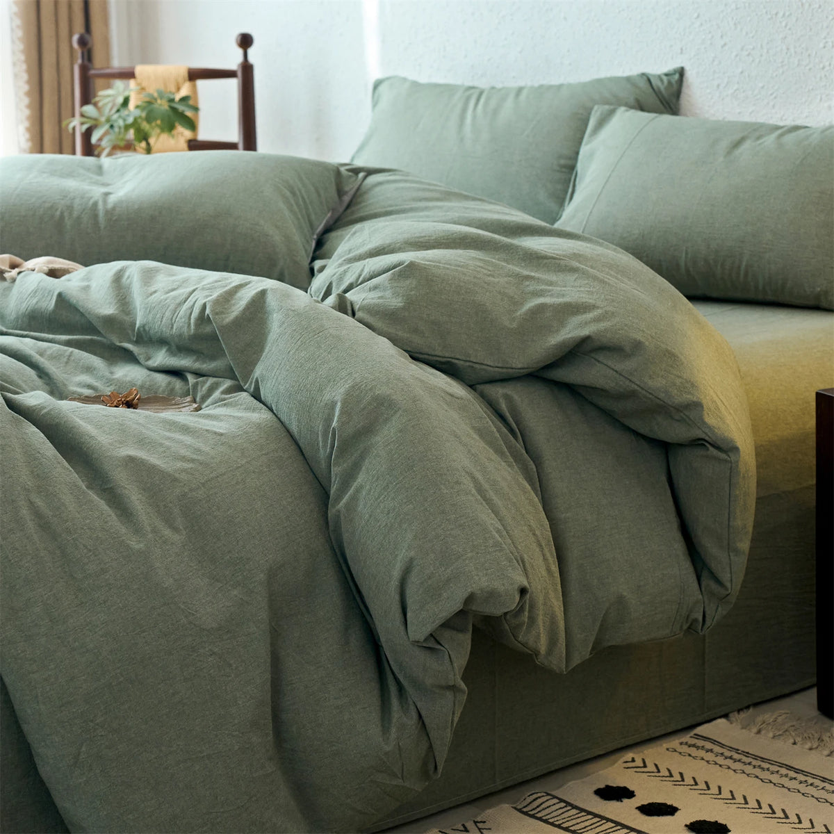 A light sage green cotton yarn-dyed duvet cover with matching pillows on a bed.