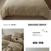 A set of soft beige cotton duvet covers and pillows displayed on a bed.