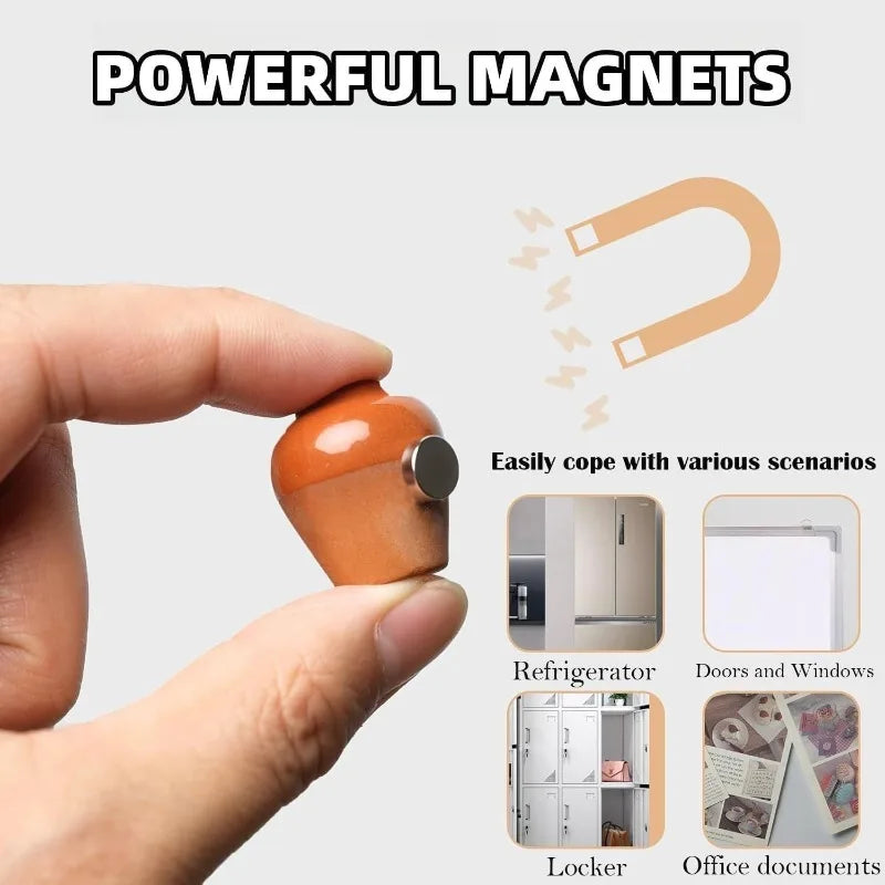 A hand holds a small, round, orange ceramic magnet used to stick various items like documents and refrigerator doors.