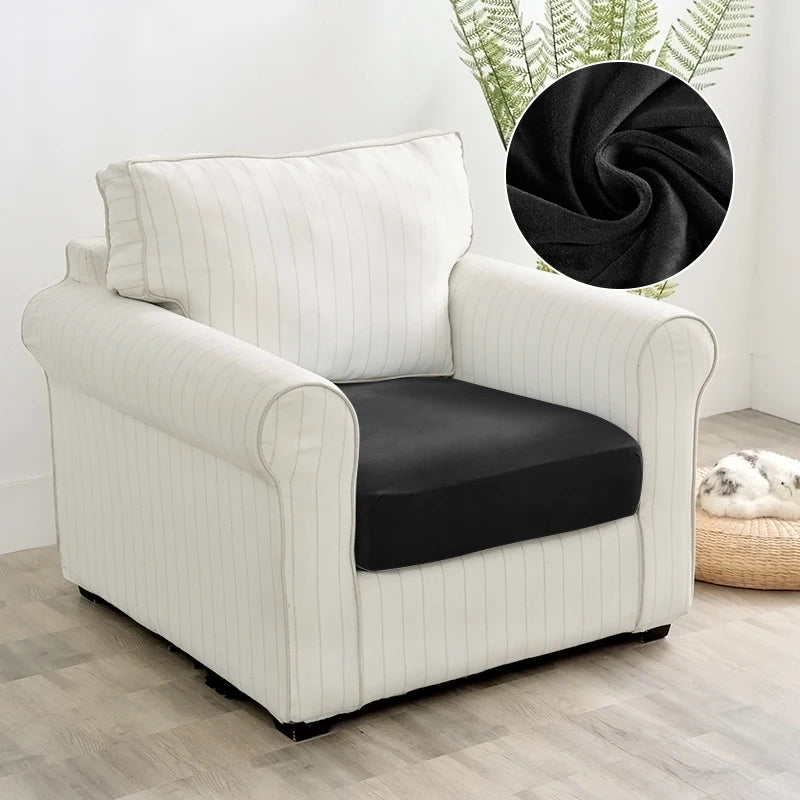 A cream upholstered armchair with black seat covers and a large black decorative sphere in the background.