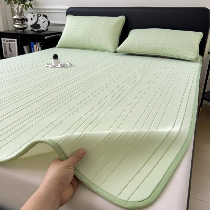A hand is touching a light green cooling ice silk bed pad on a bed, showing its ribbed texture.