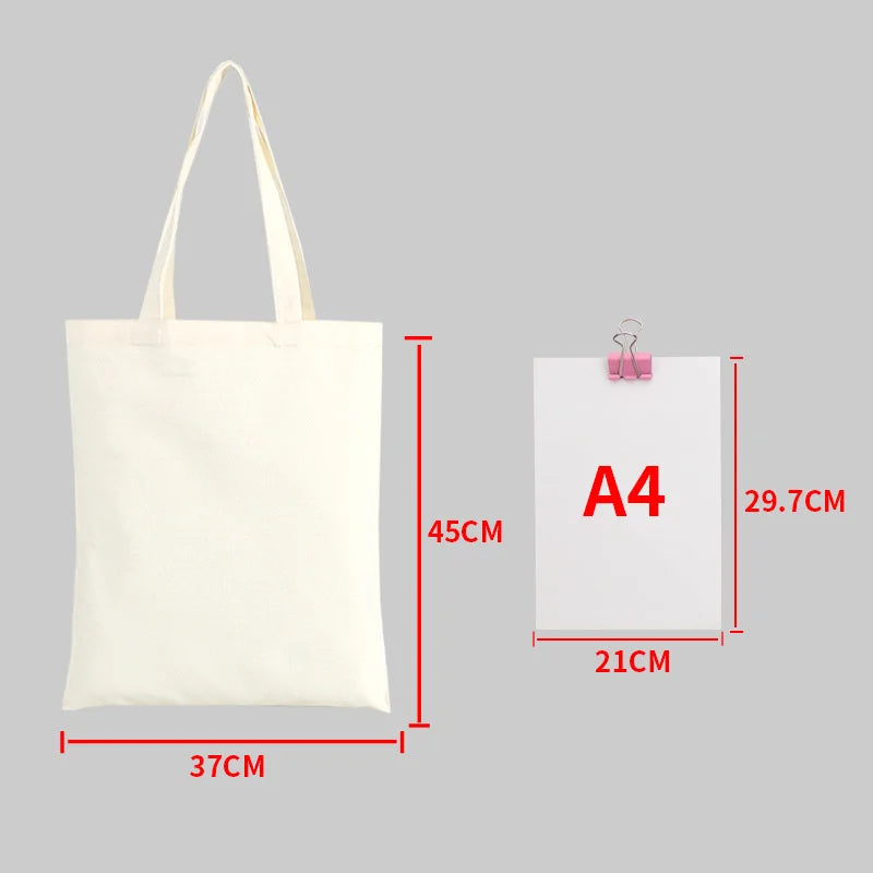 A white canvas tote bag shown next to an A4 sized piece of paper for scale.