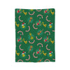 A green throw blanket featuring repeating Christmas-themed patterns with reindeer and bells.