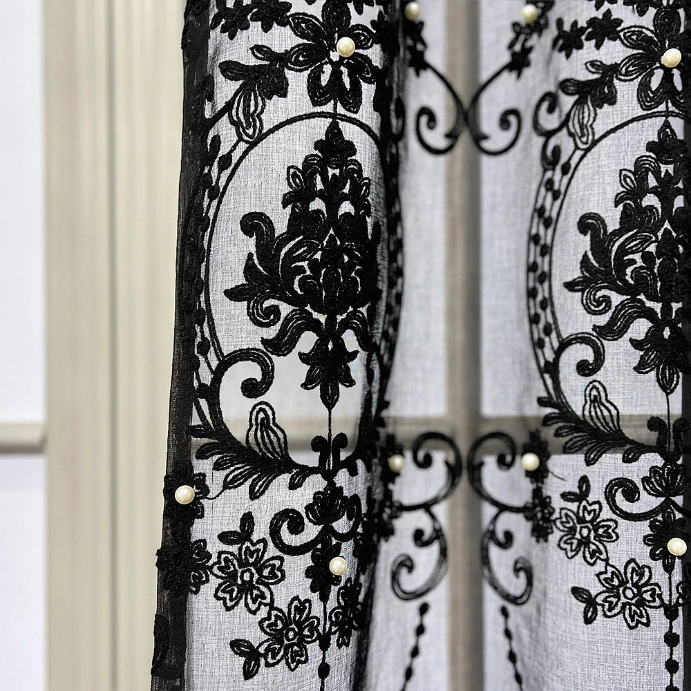 Black sheer curtain featuring intricate lace embroidery with pearl accents.