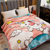 A pink and white plush fleece blanket featuring a unicorn design draped over a bed.