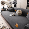 A gray fleece sofa mat with decorative pillows and a mug placed on the surface.