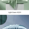 A light green silk pillowcase folded artistically on a white pedestal, next to a light blue version.
