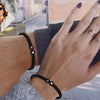 A close-up of a hand wearing several black beaded bracelets and a wristband, showing various textures and jewelry items.