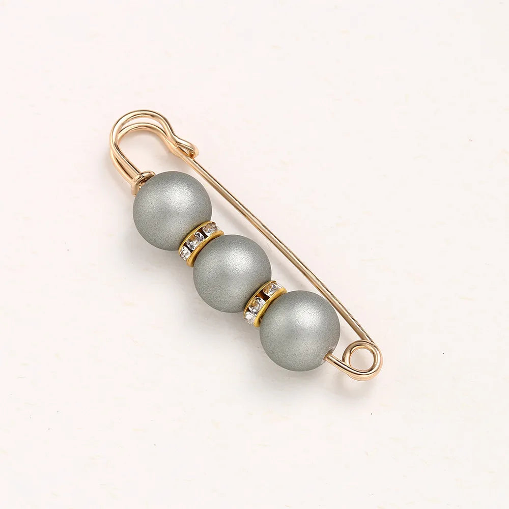 A delicate gold-toned adjustable pearl brooch featuring three spherical gray beads accented with small clear stones.