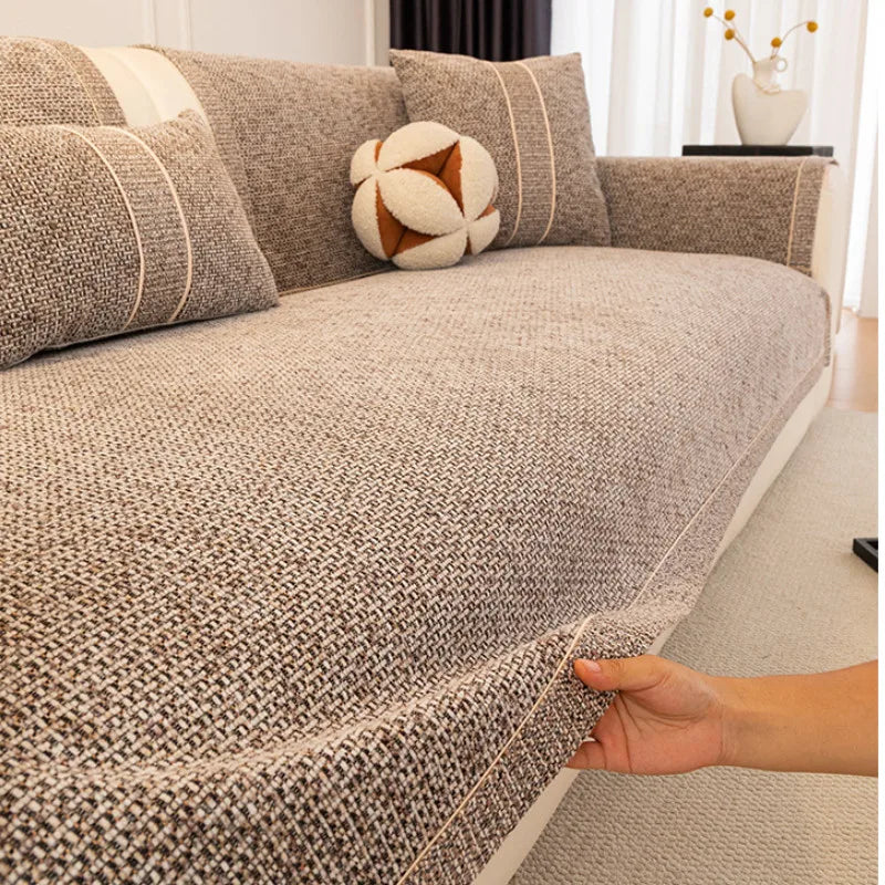 A close-up of a textured gray sofa cushion cover with decorative piping and a round accent pillow.