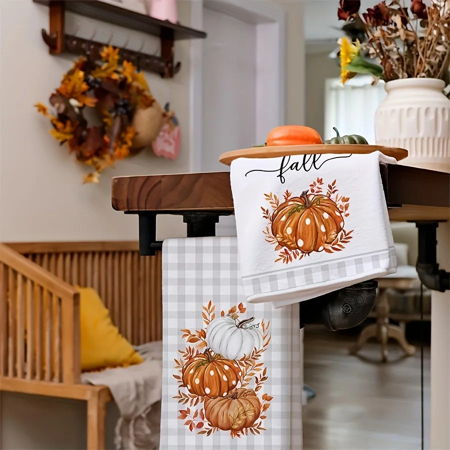 A white kitchen towel with an orange pumpkin print hangs on a wooden rack.