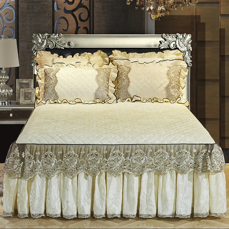 A set of three bed skirts and pillowcases featuring cream and silver lace detailing on a quilted bedspread.