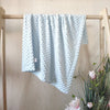 Light blue fleece swaddle blanket with a textured pattern hanging on a wooden rack.
