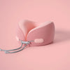 A pink U-shaped memory foam travel neck pillow with a cooling cover resting on a light pink surface.