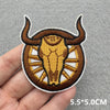 An embroidered patch of a bull's head in brown and gold tones on a gray background.