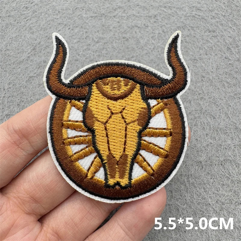 An embroidered patch of a bull's head in brown and gold tones on a gray background.
