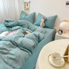 A teal duvet cover set with matching pillowcases and a stuffed animal on a bed.