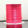 A spool of bright pink multicolor elastic beading cord lying on a white surface.