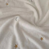 A close-up of a white soft coral fleece flannel blanket with subtle star and crescent moon embroidery.