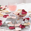 A collection of silk rose petals in shades of pink and deep red are arranged on a silver tray.