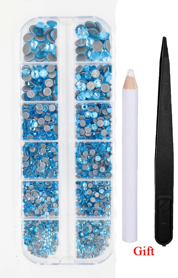 A clear plastic container holds a set of blue and silver crystal hot fix rhinestones with an applicator tool.