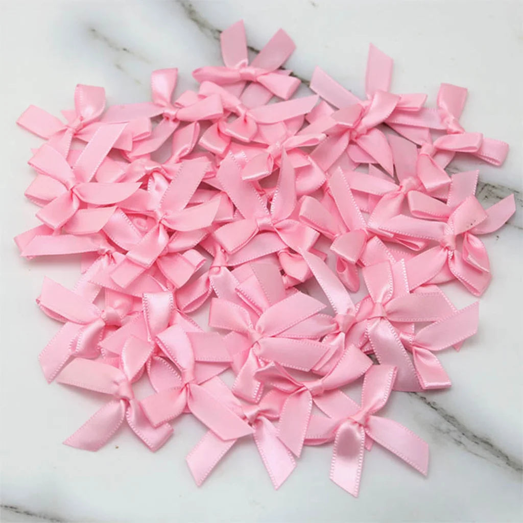 A pile of pink satin ribbon bows for crafts and decor