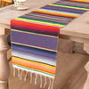 Colorful cotton Mexican sarape table runner with horizontal stripes in purple, orange, green, and yellow.