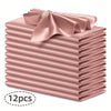 A stack of twelve silky satin pink dinner napkins with a decorative bow on top.
